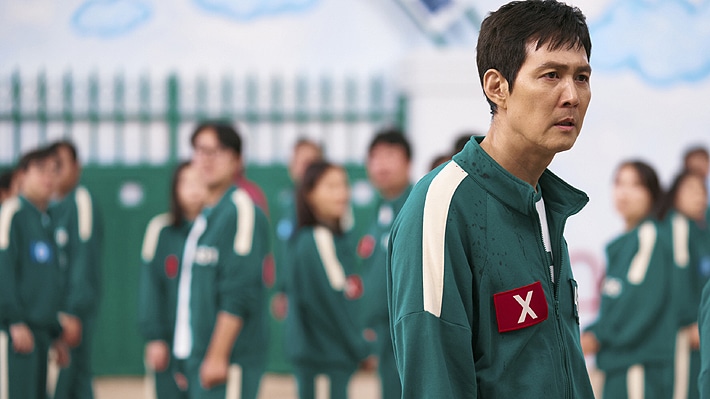 Un personaje misterioso de "El Juego del Calamar 2" con fondo oscuro y elementos del juego.