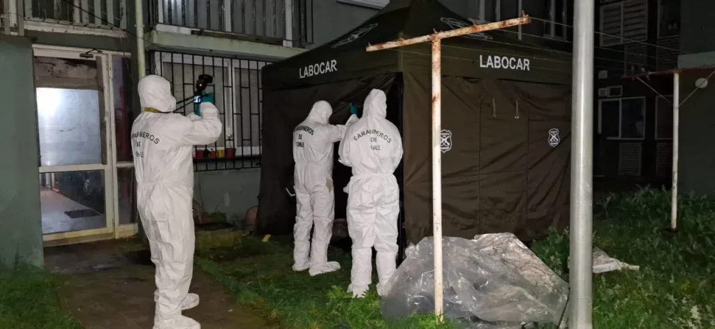Vehículos de emergencia (SAMU y Carabineros) estacionados frente a un edificio de departamentos durante la noche en Talcahuano.
